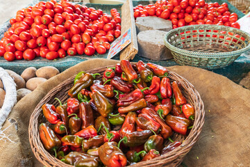 Chili peppers and tomotoes for sale at an outdoor market.