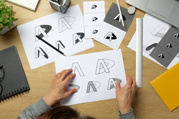 A graphic designer develops a logo for a brand. The illustrator draws sketches on paper.	 - 639394425