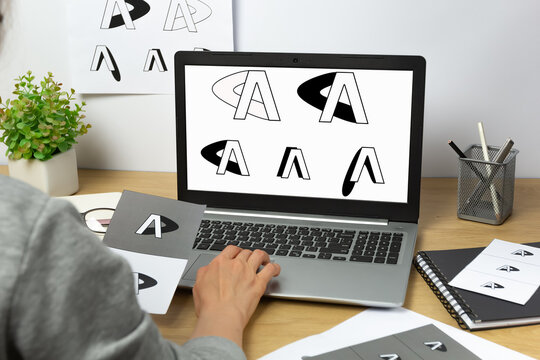 A graphic designer develops a logo for a brand on laptop.