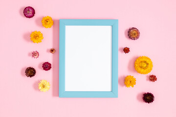Floral background with beautiful flowers. Flat lay, top view of photo frame and flowers on pastel pink background.