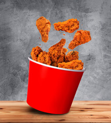 Hot Wings -Fried Chicken wings pieces fall into Bucket - large box on table in restaurant