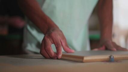 One concentrated young black carpenter engaged with his work, trimming piece of wood. Apprentice craftsmansh working at carpentry workshop with machine