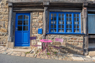 Fototapeta na wymiar Blue window and door with a pink iron table in Treguier, Brittany