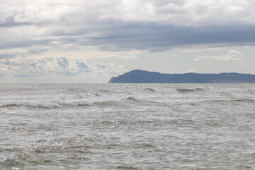 Seascape with sea waves and blue sky with clouds, Italy