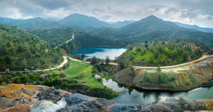 Abandoned mining area restoration in Cyprus. Panorama of open pit Memi sulphides mine with pit lake and colourful mine tailings on the foreground