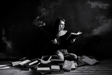 A relaxed woman sitting, smoke and reads in a room full of books. Black and white.