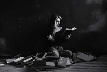 Fototapeta na wymiar A relaxed woman sitting, smoke and reads in a room full of books. Black and white.