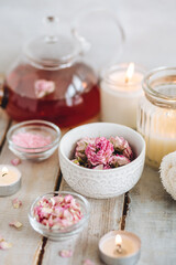 Fototapeta na wymiar Aromatherapy. Organic natural floral, plant ingredients for spa treatment in salon. Rose petals, essential oil, burning candles, towels, delicious herbal tea, Atmosphere of relax, detention.