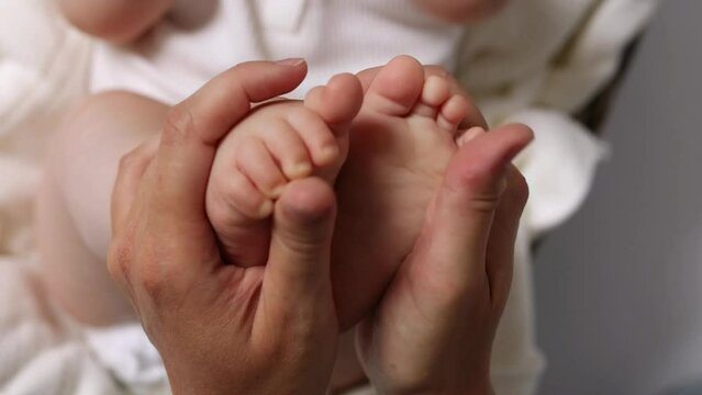 mom holds baby's small legs in her hands, close-up. High quality 4k footage