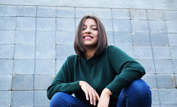 Mujer feliz y sonriente frente a una pared de color gris.