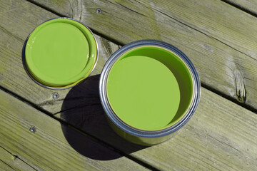 A tin can with green paint on a wooden surface