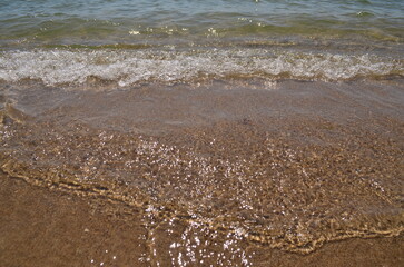 Sea water splashes on the shore under the sun