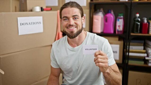 Young hispanic man holding volunteer paper smiling at charity center