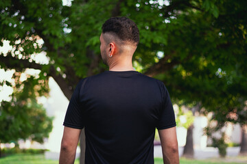 Hombre de espaldas entrenando con playera negra en el parque 