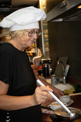Elderly retired woman in her 60s, blonde and Caucasian, wearing glasses, cooking in her spare time, for her grandchildren