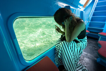 Woman sit in glass bottom boat next looking at the bottom of Adriatic sea off the coast of Split....