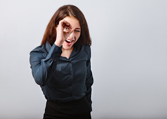 Happy excited business brunette woman doing spyglass sign looking in fingers near the eye in office...