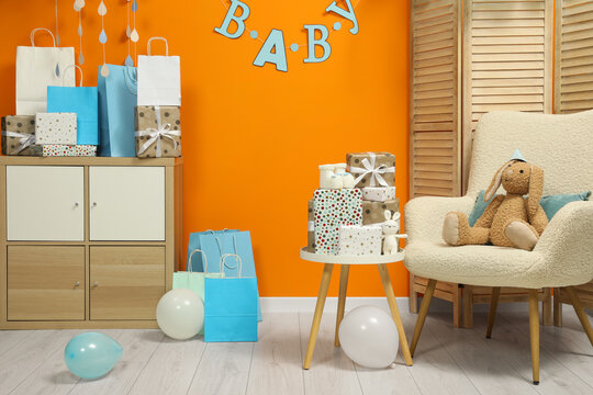 Baby shower party. Festive decor, booties, toys and gift boxes in stylish room