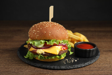 Delicious burger with beef patty, tomato sauce and french fries on wooden table