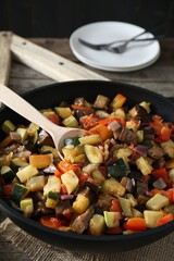 Delicious ratatouille and spoon in baking dish on table, closeup