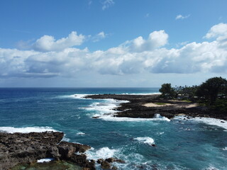 Aerial view of a beach with rocks and waves reaching Hawaiian coast