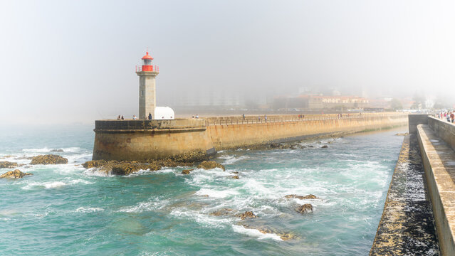 A pier and a lighthouse in a foggy day  in Porto, Portugal in august 2023