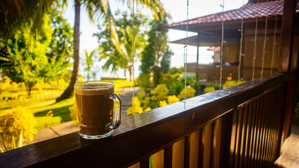 a glass of hot coffee on the fence of the house