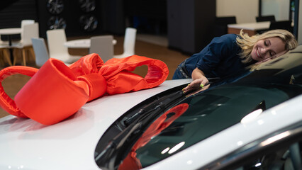 Happy caucasian woman hugging a new car. Car as a gift.