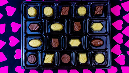 delicious chocolate surrounded by pink hearts on black background