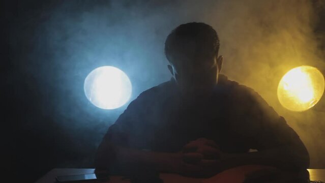 Filmic shot of a man in a red t-shirt sitting on a table preparing for a stealth mission packing his weapons and knives. Cinematic Full HD stock footage in ProRes.
