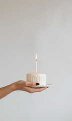 Hand holding birthday cake with lit candles, minimalistic  food photography