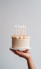 Hand holding birthday cake with lit candles, minimalistic  food photography - obrazy, fototapety, plakaty