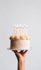 Hand holding birthday cake with lit candles, minimalistic  food photography