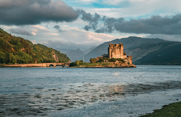 Fototapeta na wymiar The view of the Eilean Donan Castle in the twilight from the lakeshore of the Loch Duich