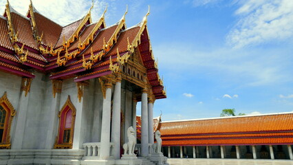 Wandelgang mit vielen Buddha Statuen im Wat Benchabophit Tempel in Bangkok bei blauem Himmel