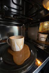 dirty coffee cup after operating with microwave oven, heating water in microwave can be dangerous, image shot with ultra wide angle lens