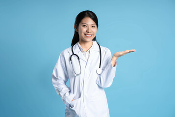 image of asian female doctor posing on blue background - Powered by Adobe