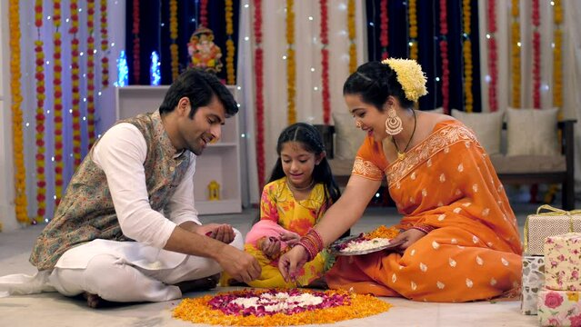 An Indian nuclear happy family makes rangoli with flowers and petals - Diwali festival  Indian festival  decorated colorful house. Indian stock video of celebrating Diwali festival at home decorate...