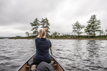 blonde Girl Canoe ride exploring nature on morning mist Kejimkujik National Park Wilderness Nova...