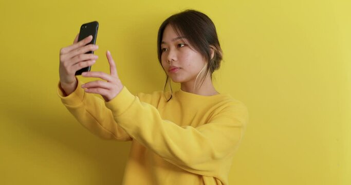 sad unhappy Asian teenager in sweater testing checking new smart phone camera Young woman learning to taker selfie, looking at screen Gadget Girl sending her photo to friend, online chat, acquaintance