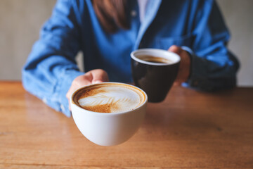 Closeup image of a woman holding and serving two cups of hot coffee