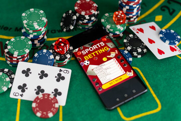 Chips and playing cards for gambling games with mobile phone on color background