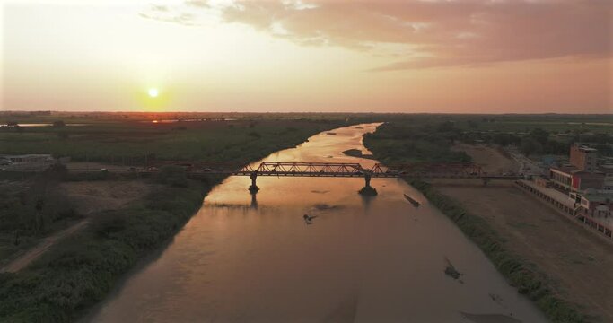 Aerial shot of Tumbes river, bridge and city at sunset. Tropical city at north of Per&uacute;. 