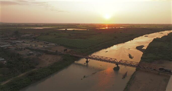 Aerial shot of Tumbes river, bridge and city at sunset. Tropical city at north of Per&uacute;. 