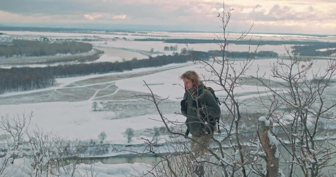 lonely guy exploring nature on top of mountain, looking at distance, standing on hill slow motion Guy leads active lifestyle, Sport, hicker is in the summit. a journey through the mountains in winter.