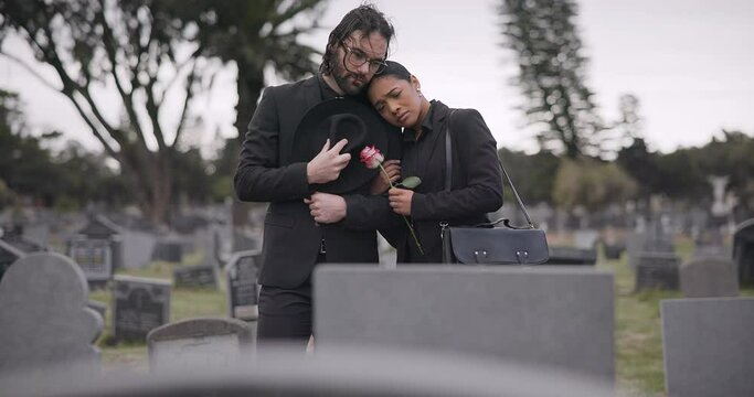 Couple, sad and mourning at tomb of graveyard, funeral and pay respect together outdoor. Death, grief and man and woman at cemetery by casket, empathy and interracial support to console at tombstone