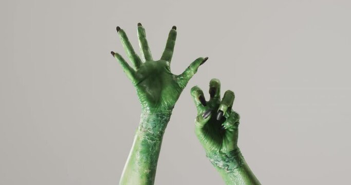 Video of halloween green monster hands with copy space on grey background