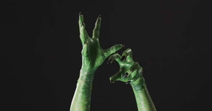 Video of halloween green monster hands with copy space on black background