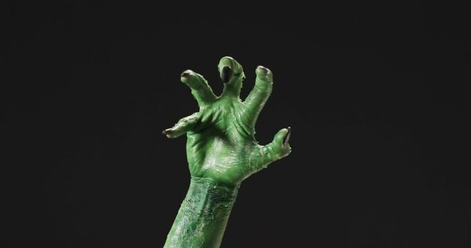Video of halloween green monster hand with copy space on black background