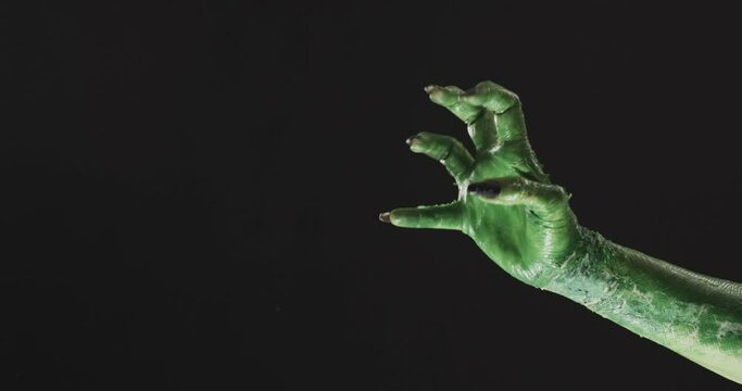 Video of halloween green monster hand with copy space on black background